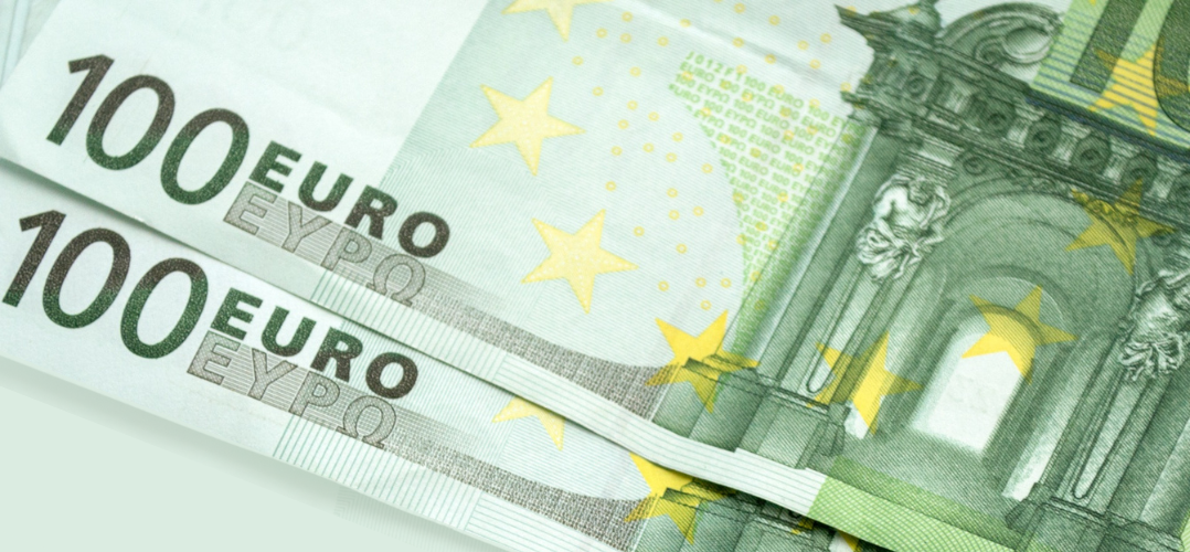 Das Bild zeigt zwei 100-Euro-Banknoten, die nebeneinander auf einer flachen Oberfläche platziert sind. Die Banknoten sind grünlich und mit komplexen Mustern und Designs bedruckt, einschließlich der Worte “100 EURO” und “ΕΥΡΩ”. Gelbe Sterne, ein charakteristisches Merkmal der Europäischen Union, sind ebenfalls auf den Banknoten sichtbar. Ein Teil eines architektonischen Designs ist auf der rechten Seite des Bildes zu sehen.