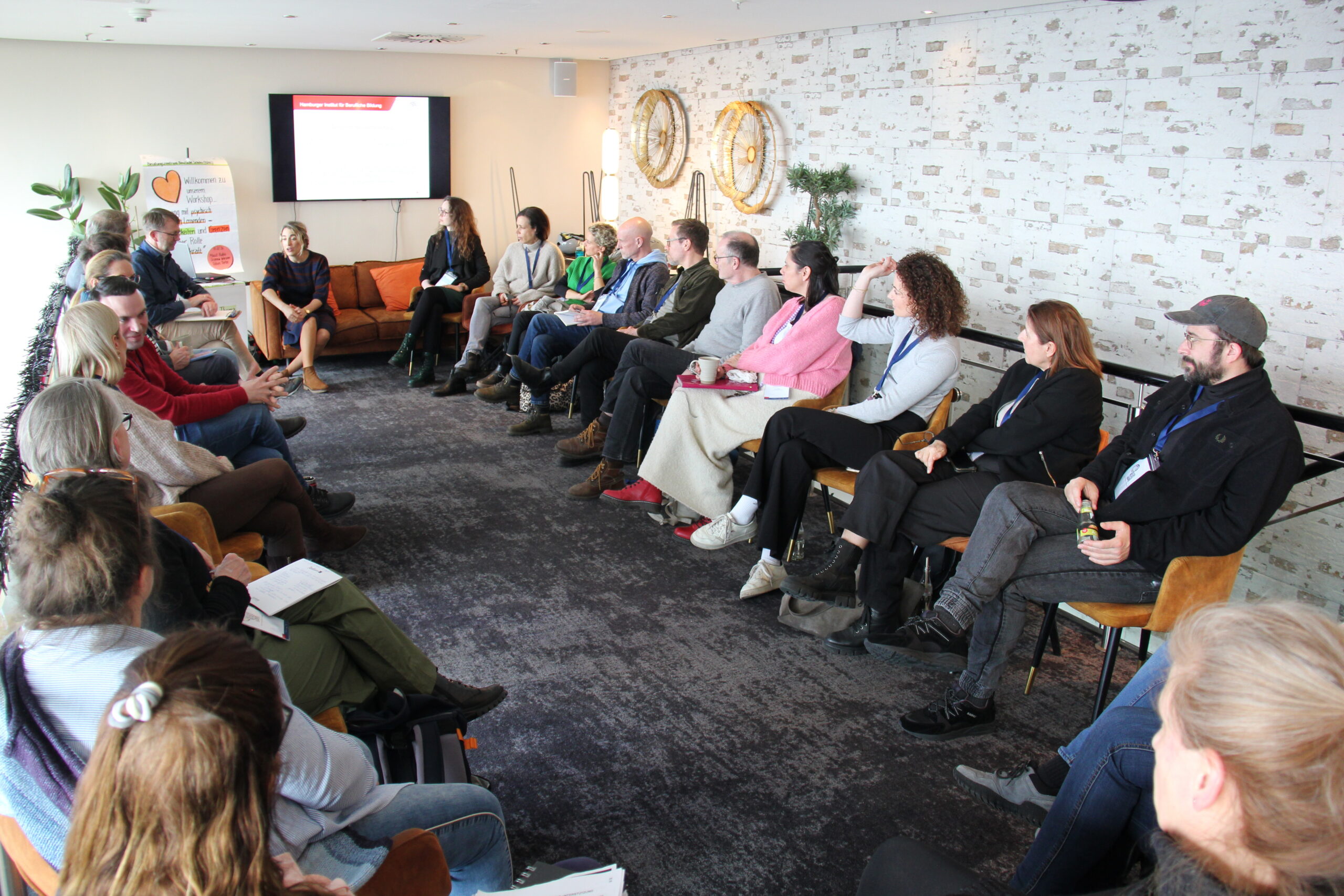 Viele Personen sitzen im Stuhlkreis.
